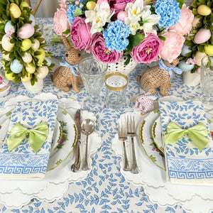 Easter-themed table setting with floral arrangements, bunny decorations, and colorful eggs.