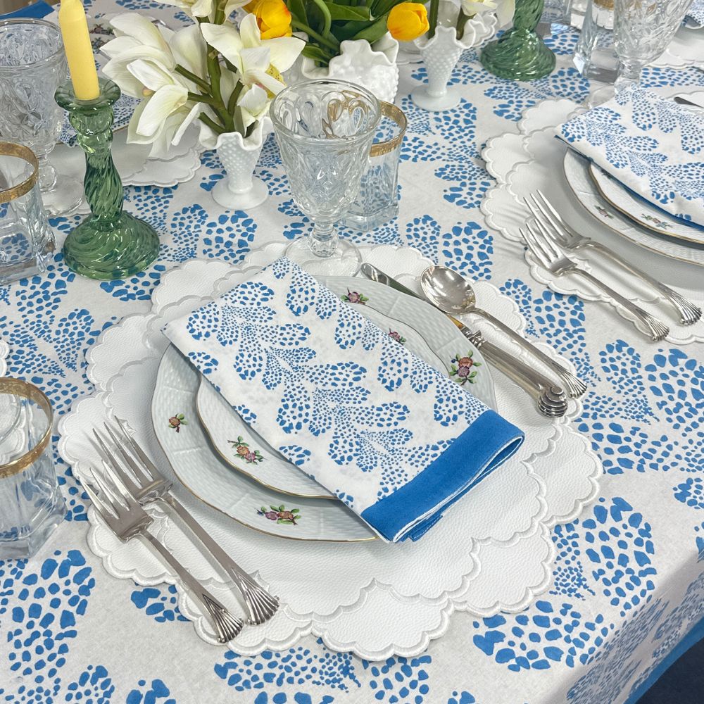 Elegant table setting with blue and white floral patterns on a tablecloth and napkin.