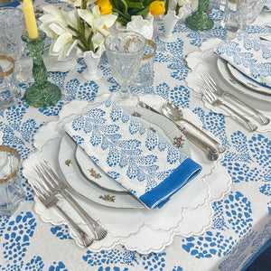 Elegant table setting with blue and white floral patterns on a tablecloth and napkin.