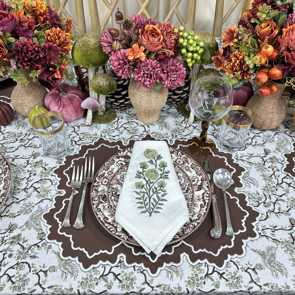 Decorative table setting with floral centerpieces, cutlery, and a patterned tablecloth.
