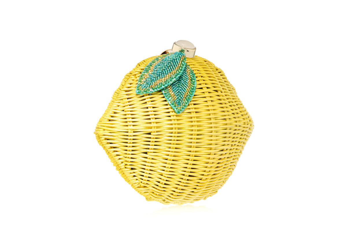 Three-quarter view of Lemon Basket Citrus Clutch showcasing a woven basket silhouette and green beaded citrus detail on white