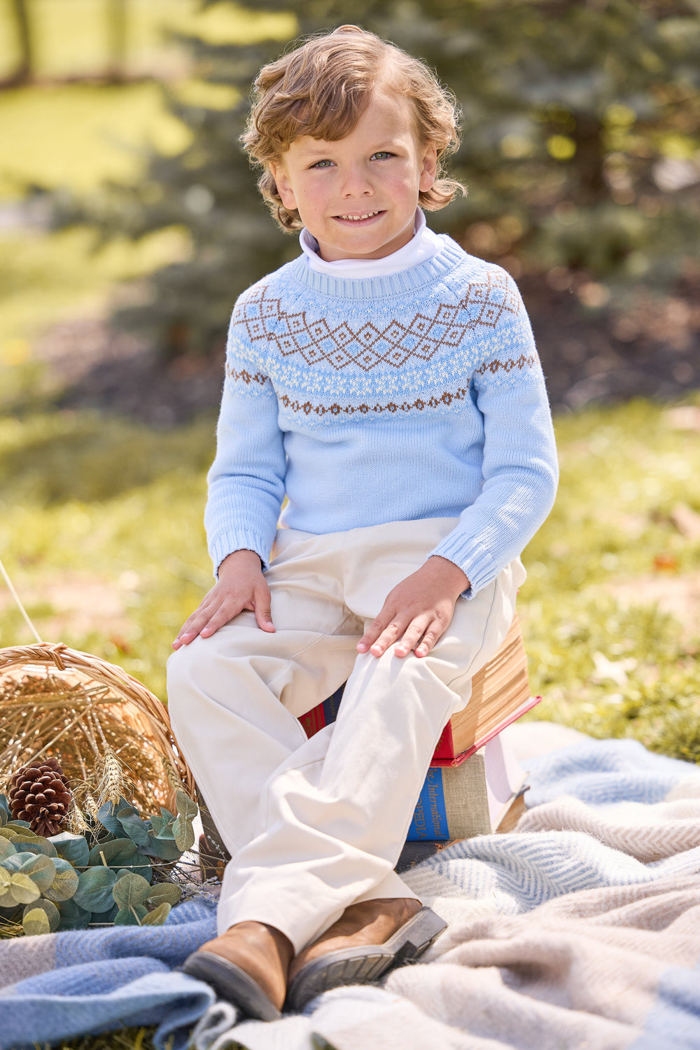 Front view of child wearing Winthrop Fair Isle sweater in light blue with cream and brown yoke and white turtleneck outdoors