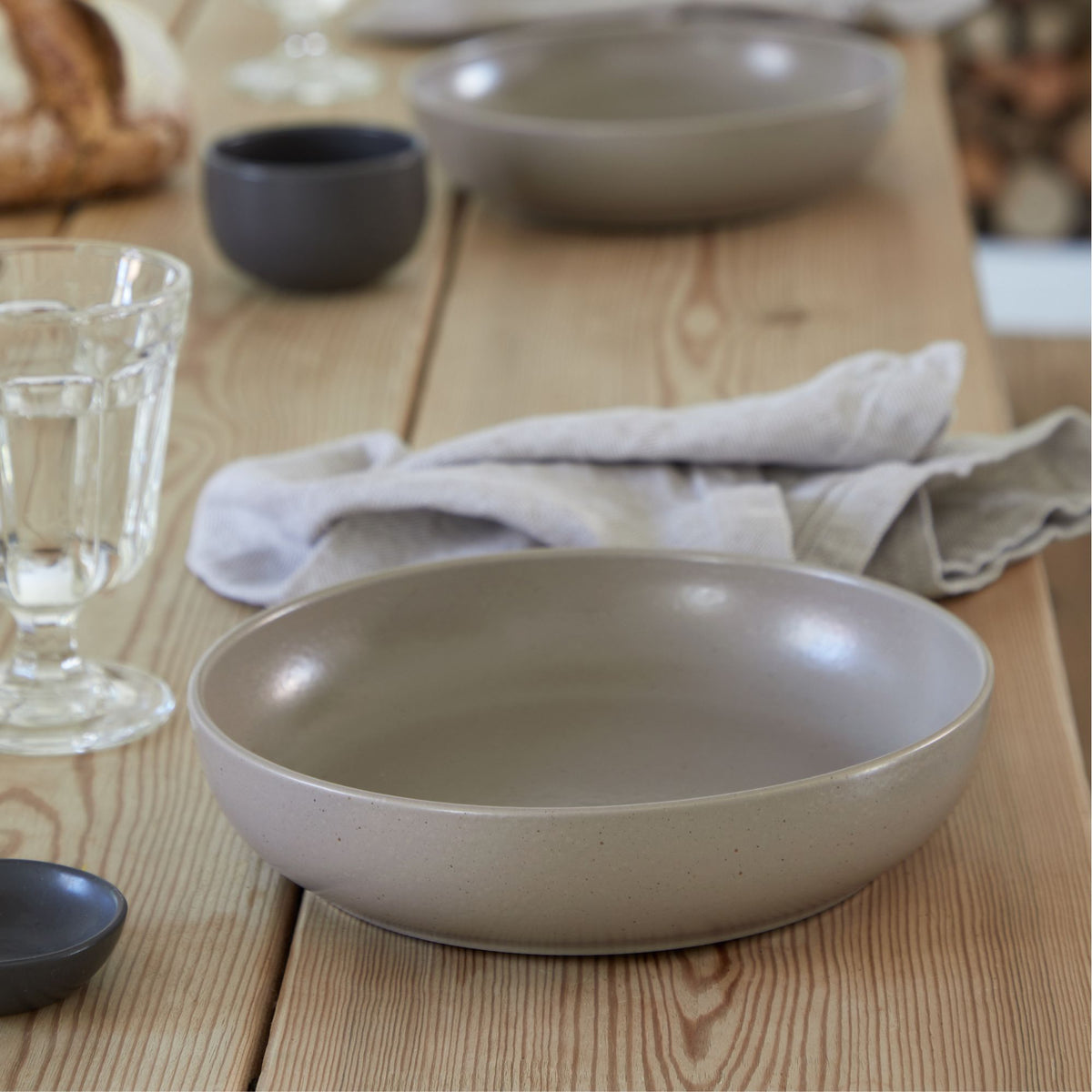 Front view of a Pacifica Collection chestnut pasta bowl showcasing matte glaze and wide shallow profile on a wooden table