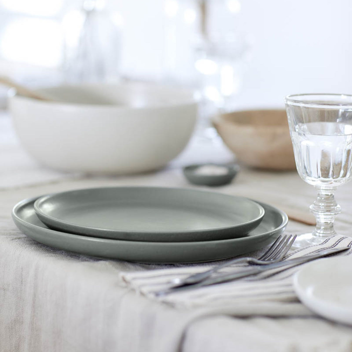 Front view of Pacifica Collection 13-inch serving bowl in artichoke showcasing matte finish and stackable design on a linen table