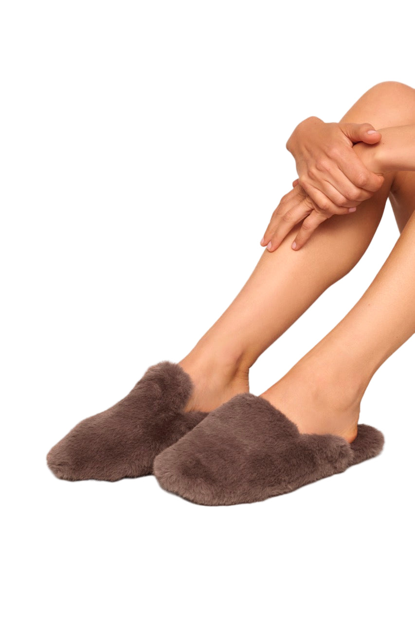 Three quarter front view of plush mule slipper in deep taupe showing fluffy faux fur upper, cushioned insole, and rubber sole on white background