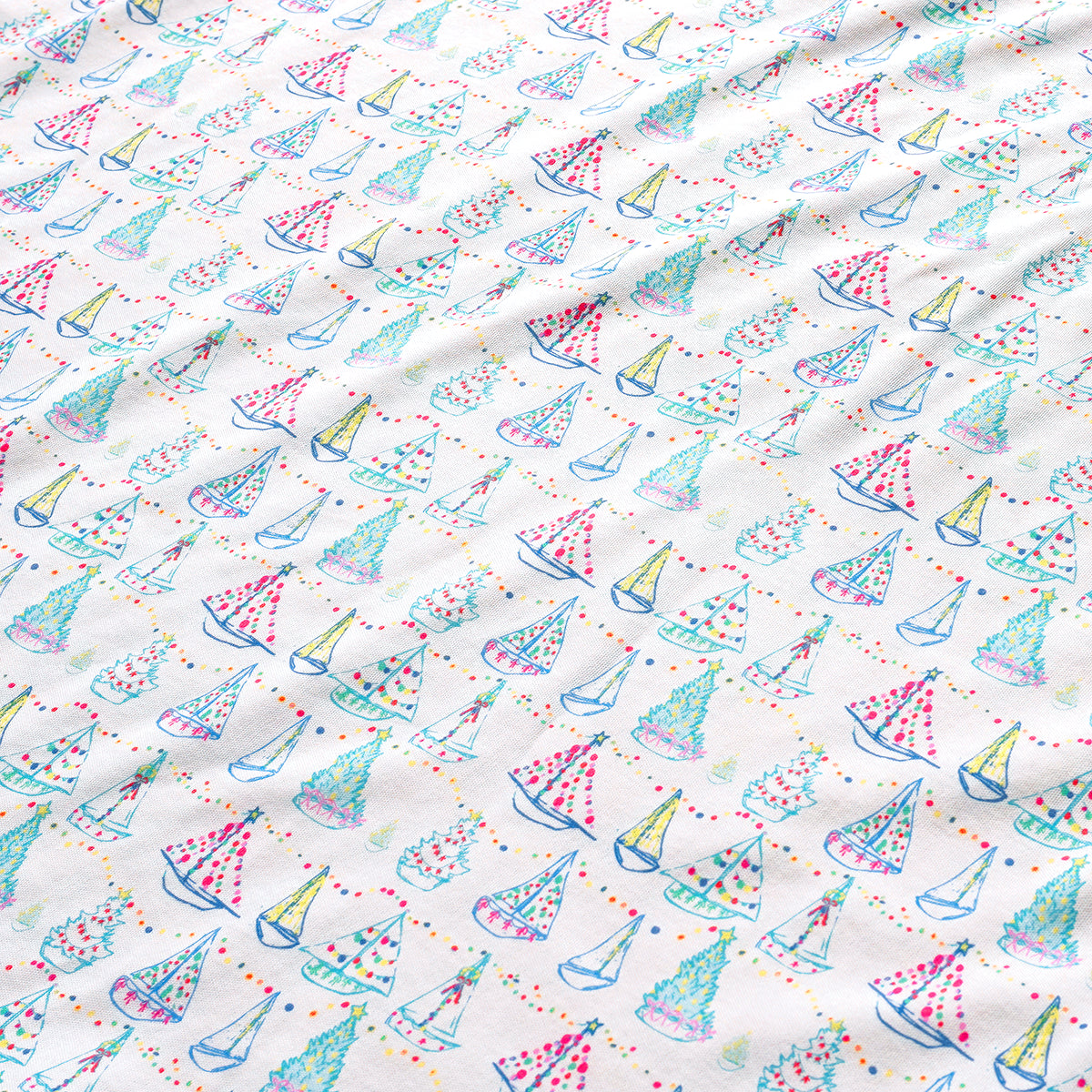 Close-up of Holiday Harbor Zip Baby Onesie with sailboats, colorful lights, garlands, and Christmas trees on white fabric