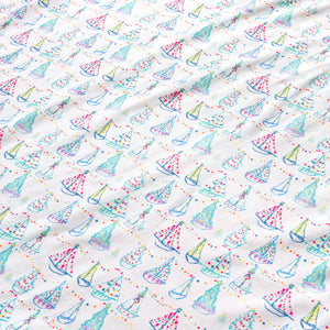 Close-up of Holiday Harbor Zip Baby Onesie with sailboats, colorful lights, garlands, and Christmas trees on white fabric
