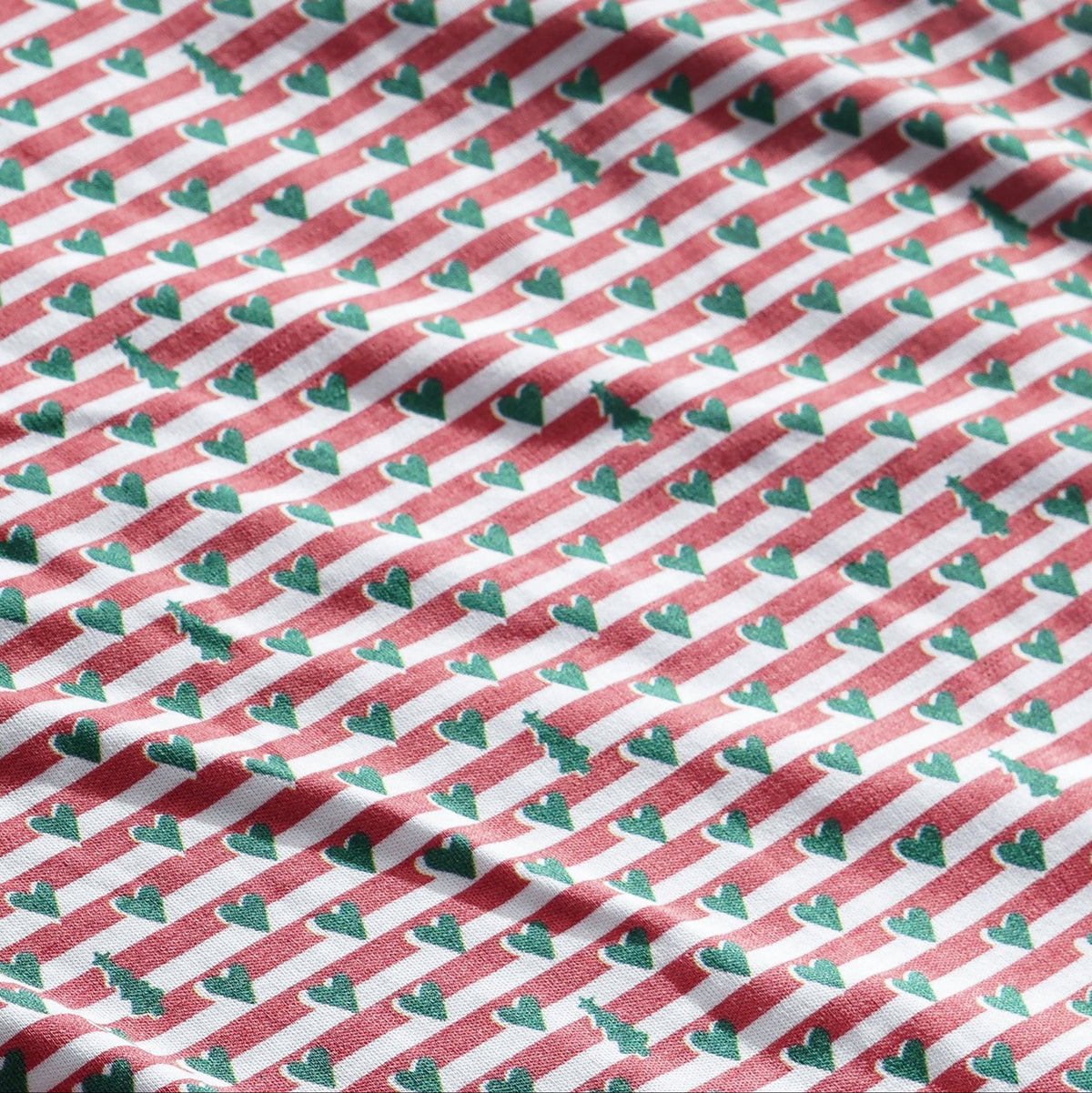 Close-up of baby bib showcasing red-and-white striped fabric with small green hearts and hidden Christmas tree motifs