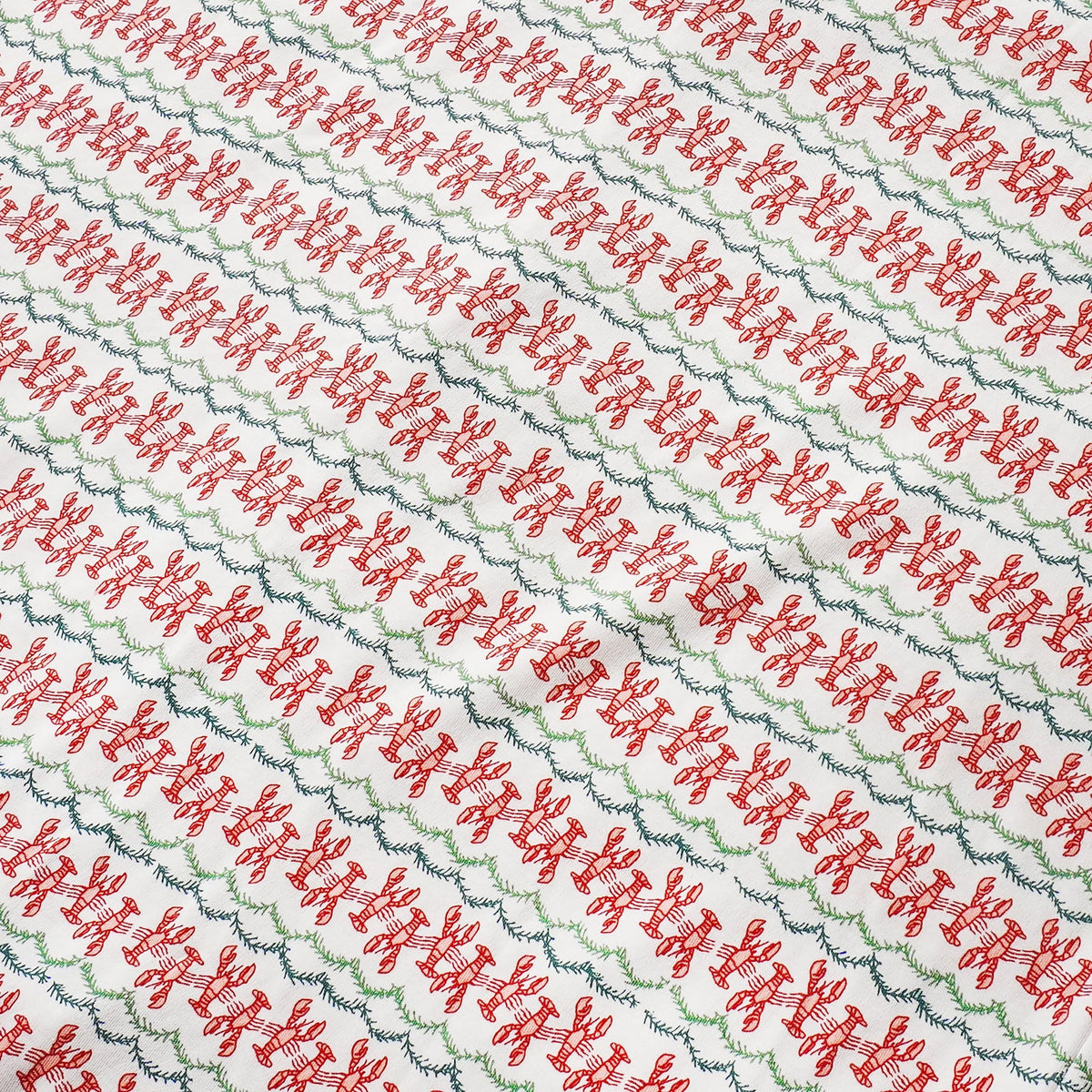 Close-up view of Christmas Lobsters Lounge Pants showcasing red lobster and green evergreen garland print on white fabric