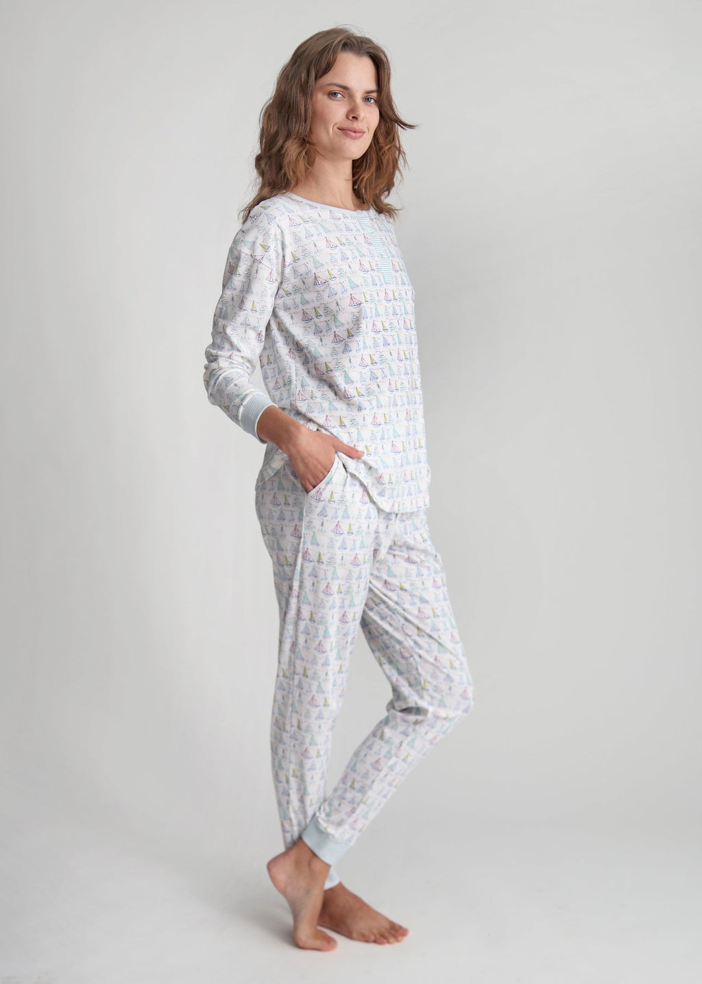 Three-quarter view of Holiday Harbor women’s henley pajama set in a light color with festive sailboat print, gray studio background