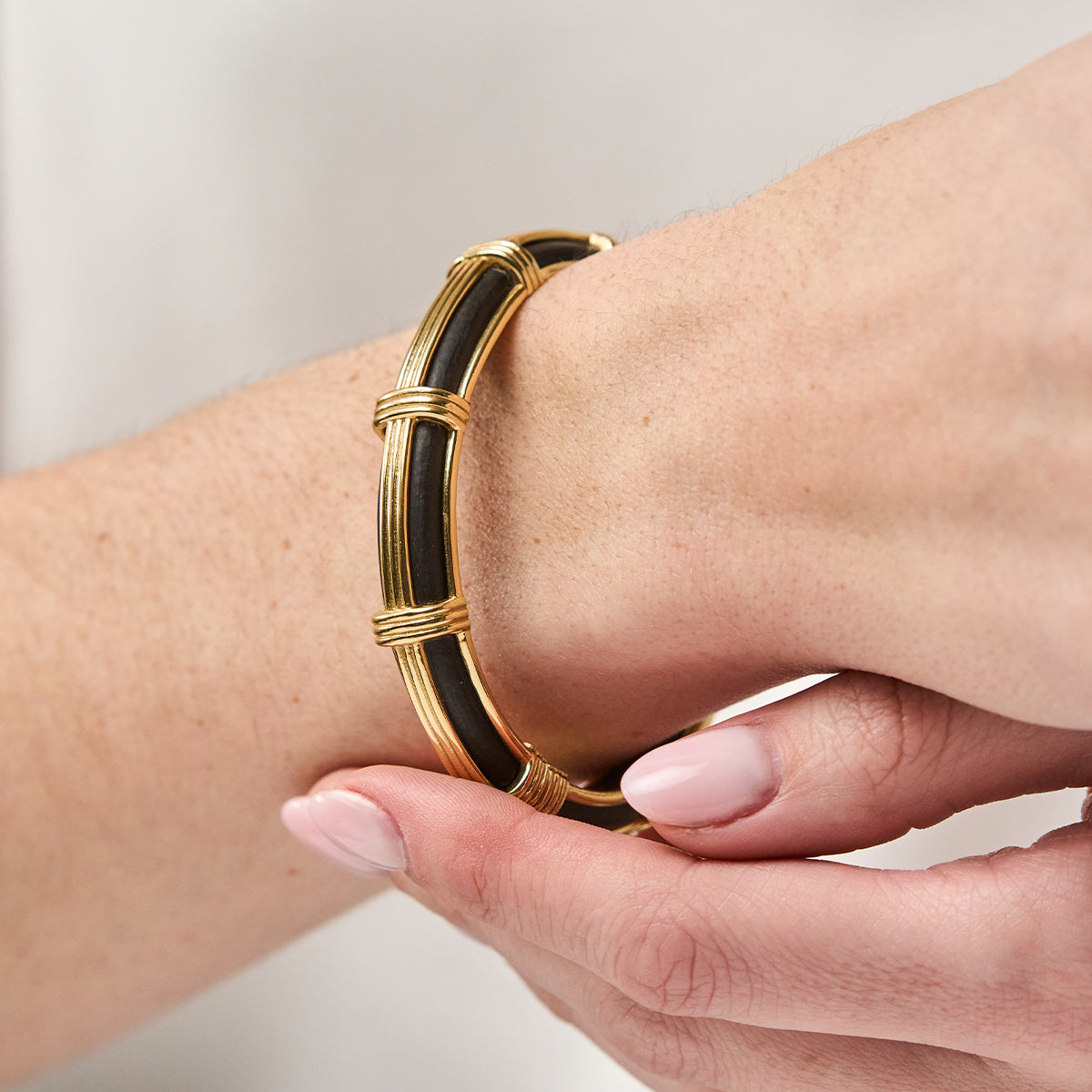 Close-up of Gaia Petite Hinged Bangle in Ebony showing carved ebony and gold ley lines on a wrist
