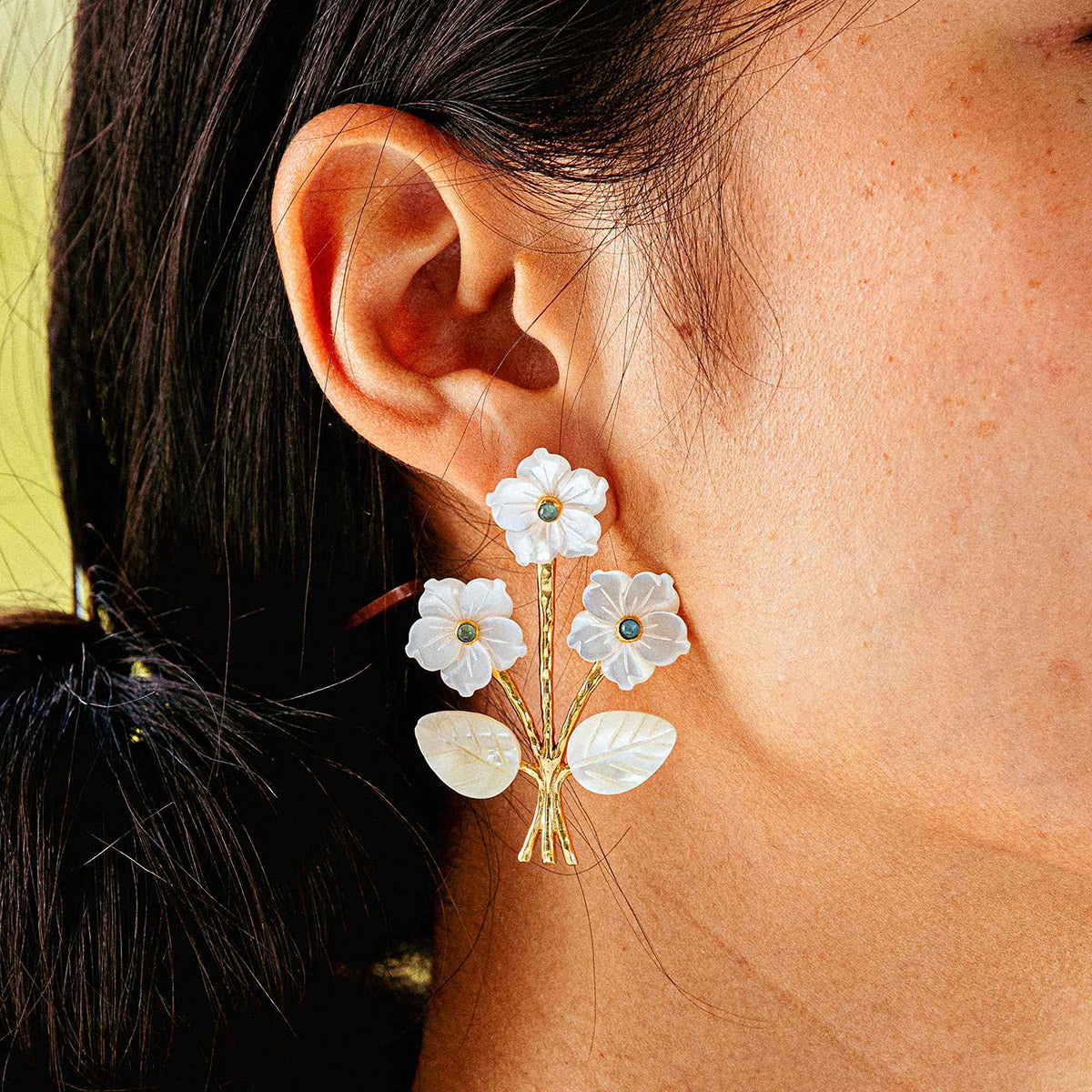 Close view of Mermaid Garden Convertible Bouquet Post Earrings with mother-of-pearl flowers on a model’s ear