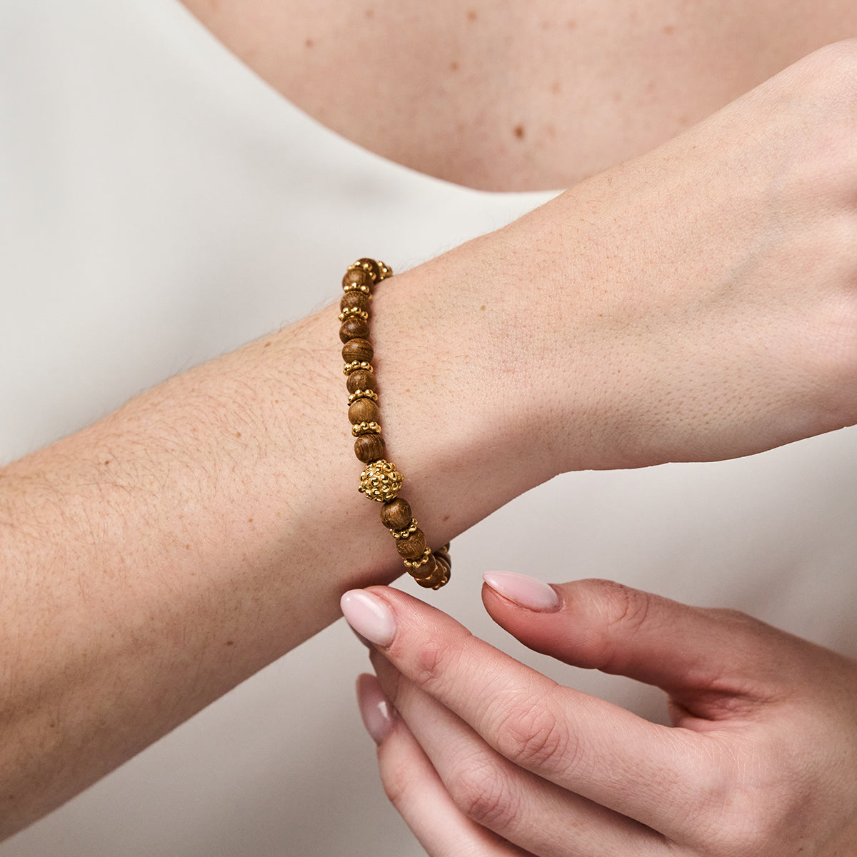 Close-up view of Berry Stretch Bracelet in Teak showcasing hand-carved teak beads and golden berries on a wrist