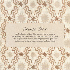 Close-up of All-Stages bassinet sheet by Nate Berkus showcasing the Bronze Star pattern with printed design details