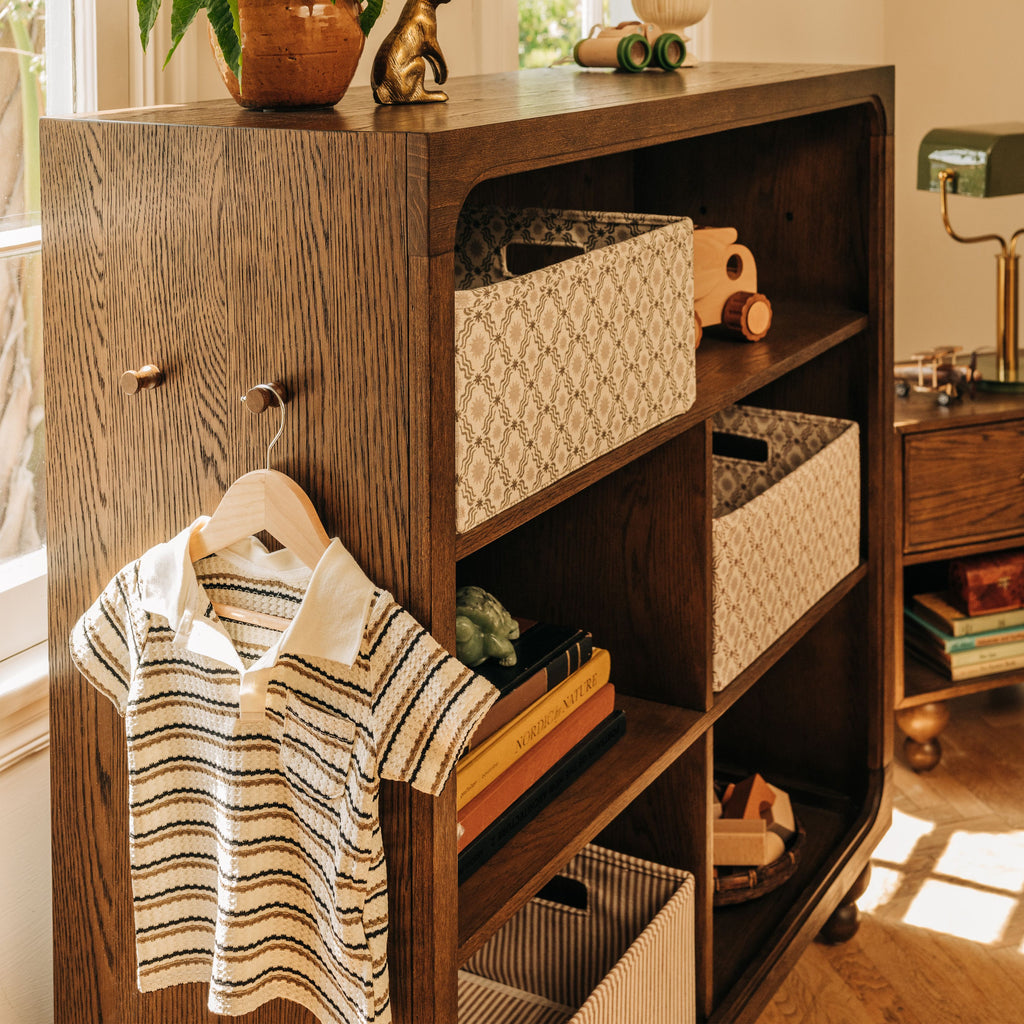 Front view of Astre Assembled Bookcase by Nate Berkus in Toffee showcasing open shelves and woven baskets in a styled room