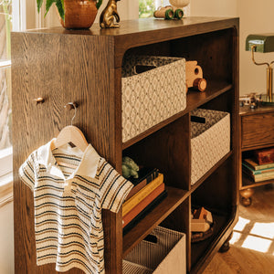 Front view of Astre Assembled Bookcase by Nate Berkus in Toffee showcasing open shelves and woven baskets in a styled room