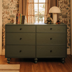 Front view of Astre six drawer dresser by Nate Berkus showcasing six drawers and round feet with patterned wallpaper