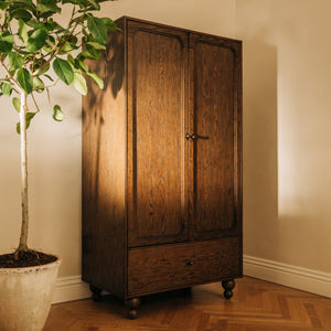 Front view of Astre assembled armoire by Nate Berkus in Toffee showcasing double doors and lower drawer with a room background