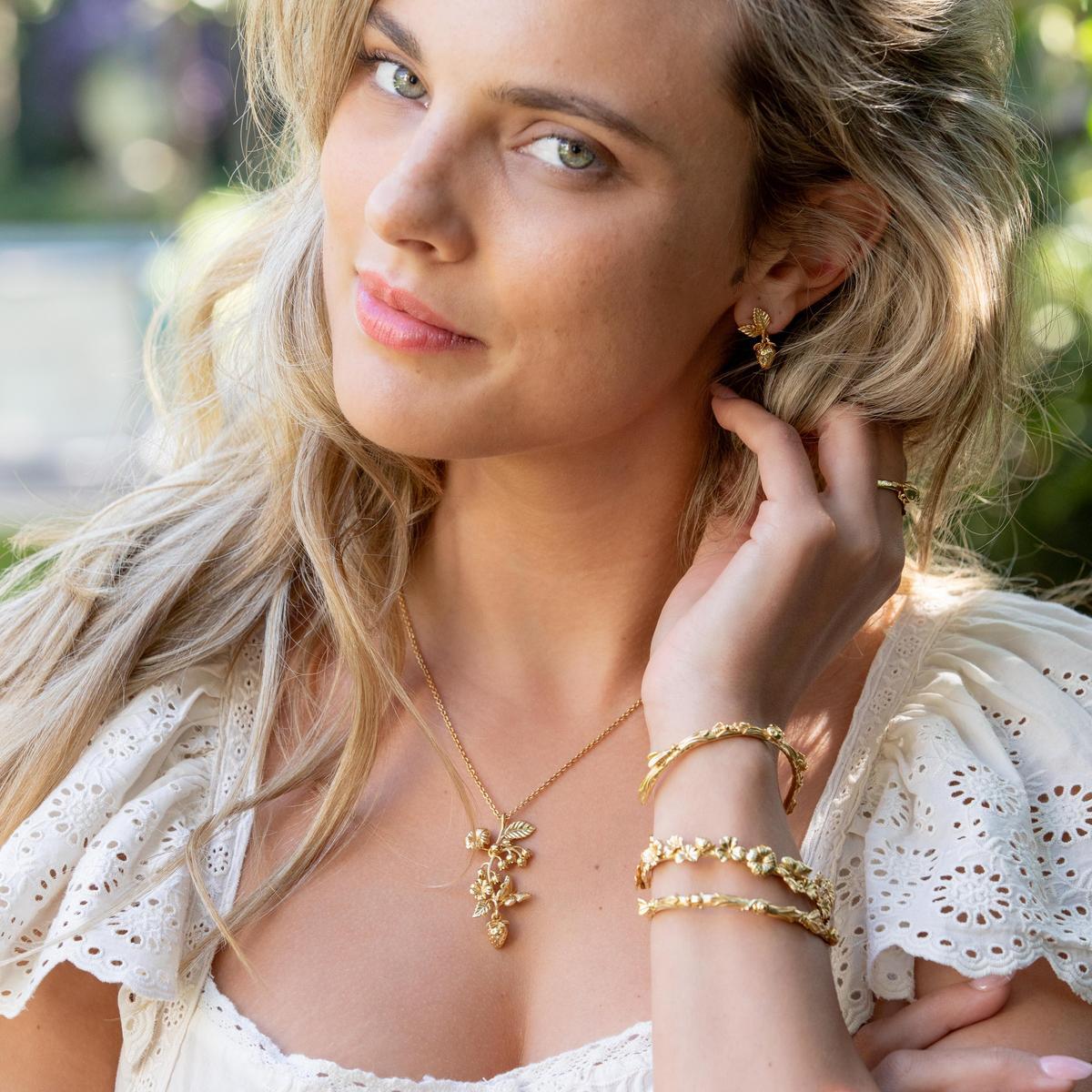 Close up of Meadow Flowers Petite Cuff in gold on a model’s wrist showing gilded wildflower and butterfly details