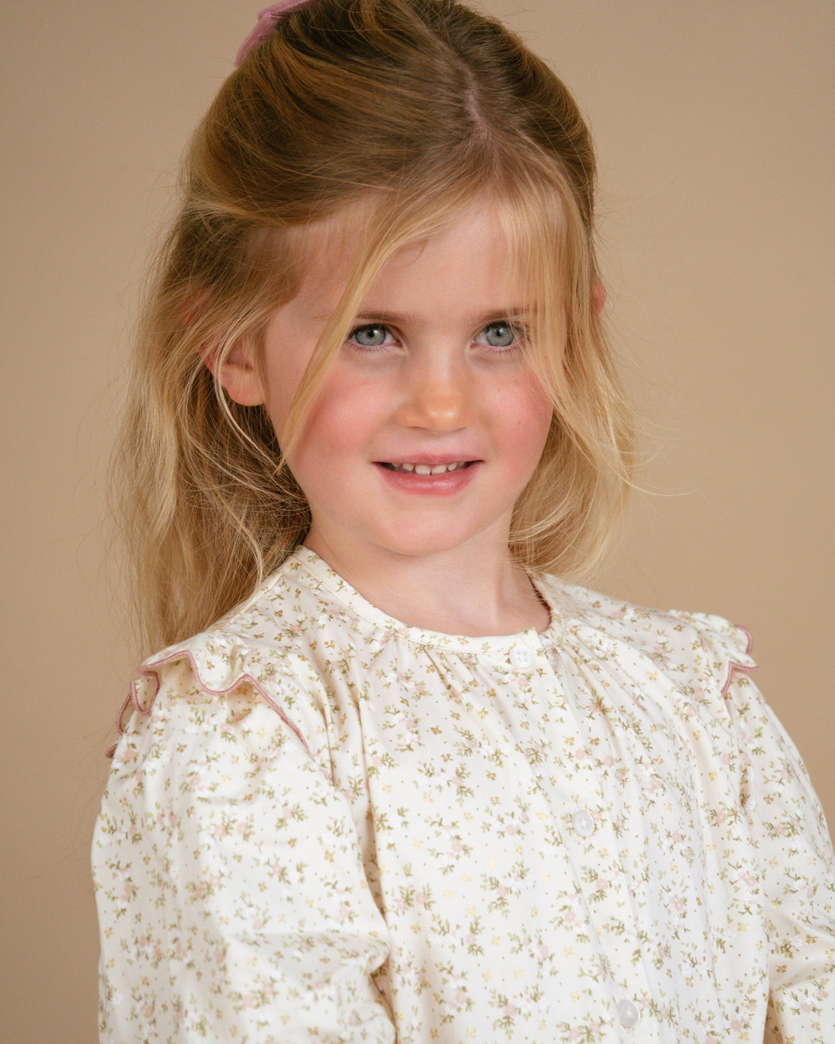 Young girl wearing a white lace dress against a beige background