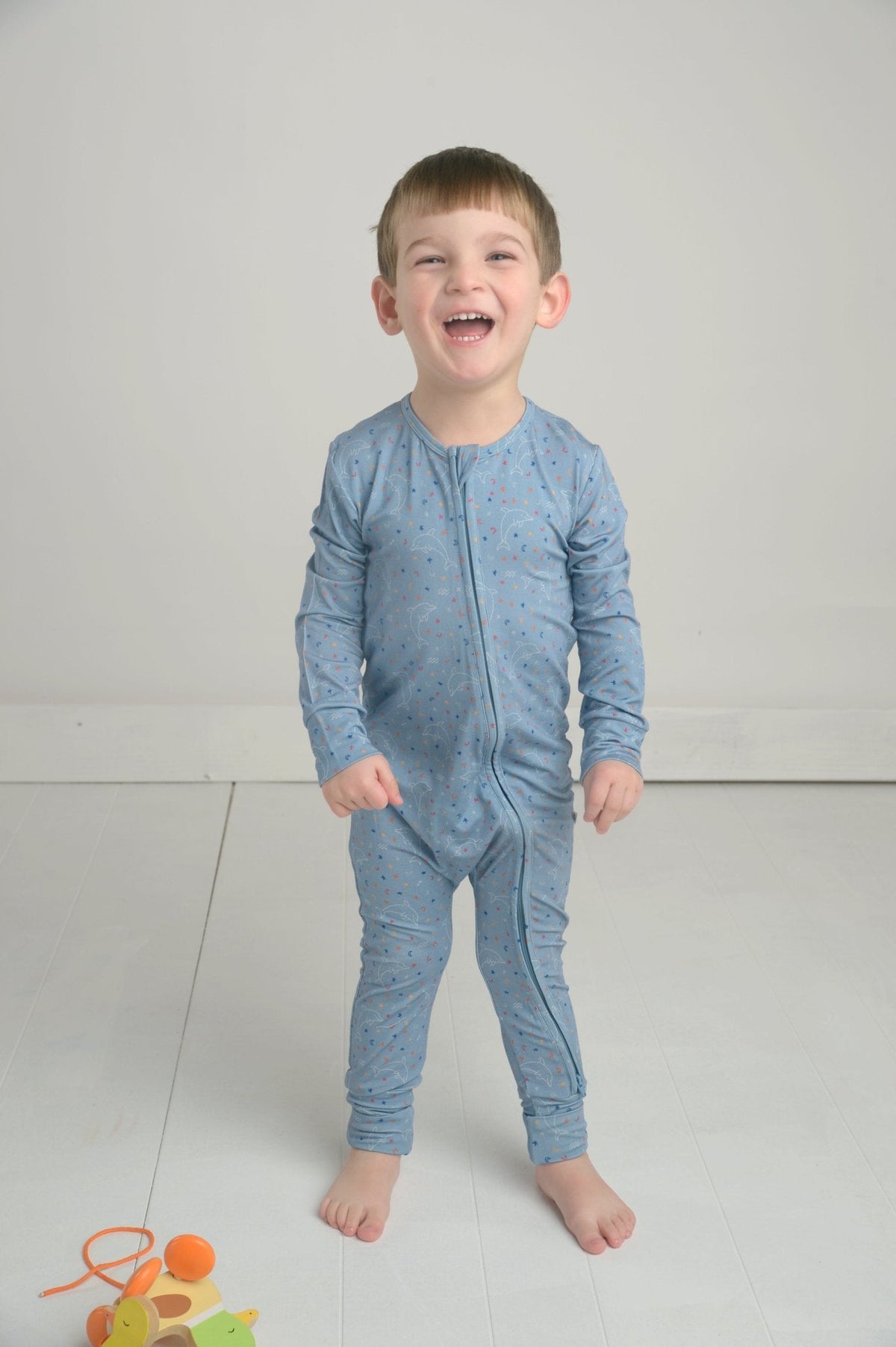 Front view of blue Aquarius bamboo romper on toddler showcasing star-sign print and front zip closure on pale studio floor