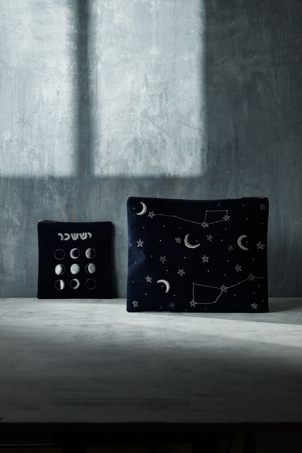 Front of Issachar tallit bag and pouch in navy velvet with silver moon and star embroidery on gray backdrop