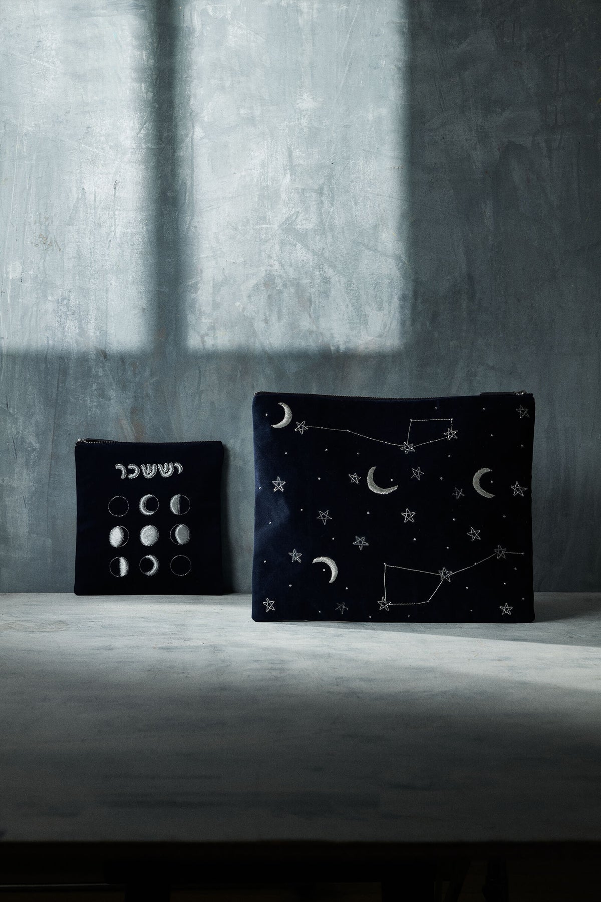 Front of Issachar tallit bag and pouch in navy velvet with silver moon and star embroidery on gray backdrop
