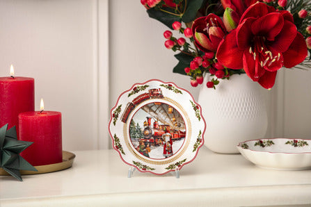 Front view of Annual Christmas Edition small bowl showing gold trim and festive scene on a white mantel with red candles