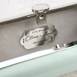 Customized wedding ring box with engraved names and date, and matching The Bella Rosa Collection Sage Green Satin Petite clutch.