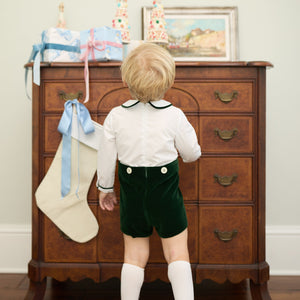 Back view of Benjamin Button On in Grafton Green Velvet showing green velvet shorts and white top with a dresser background
