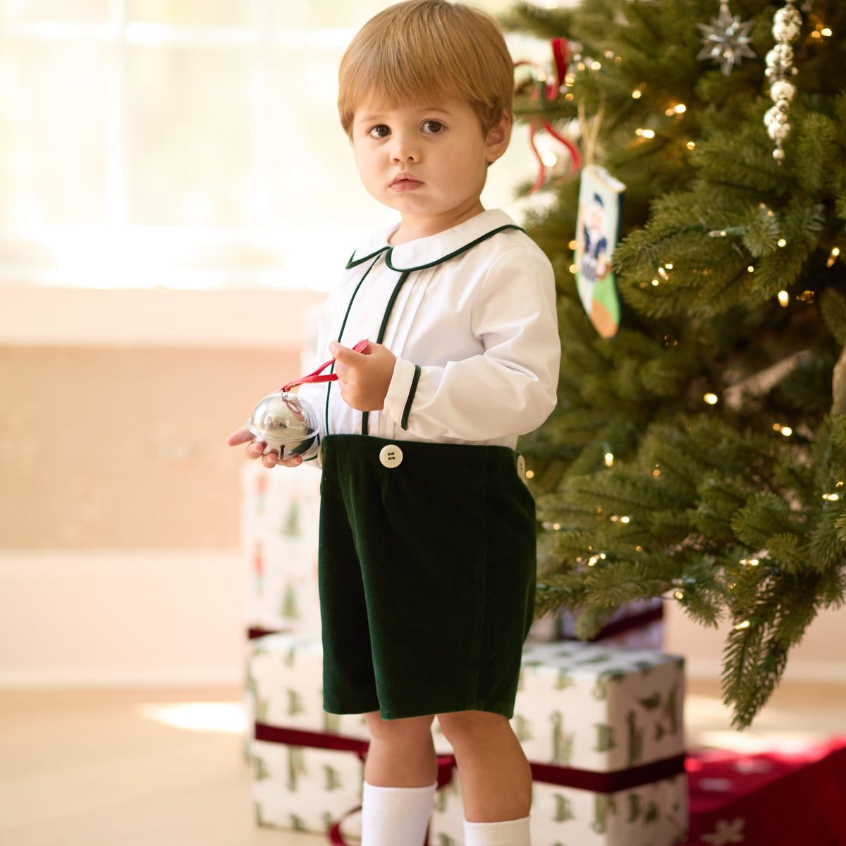 Boys’ Benjamin Button On with crisp white long-sleeve cotton poplin top, Grafton Green piping and pintuck details, paired with Grafton Green Velvet shorts and signature HD buttons.