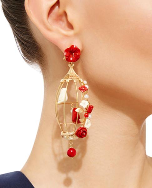 Side view of Lovebirds earrings showing gold birdcage design with red flowers, pearls, and a dangling red bead on a model’s ear