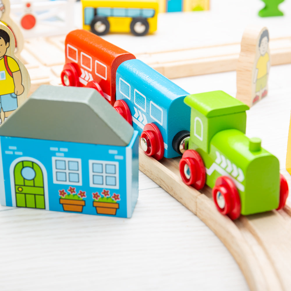 Close-up view of Town and Country Train Set showcasing colorful wooden train cars and track with a blue station house