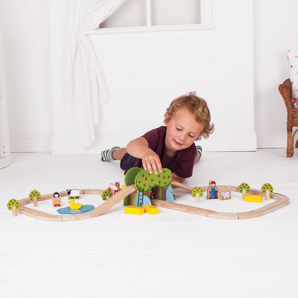 Child playing with the Farm Train Set on a wooden railway track with farm scenery