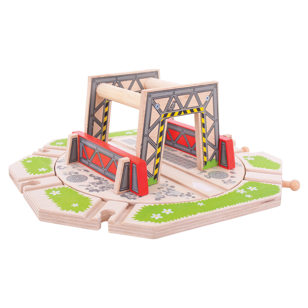 Three-quarter view of Industrial Turntable wooden train accessory showing rotating platform, painted track entrances and red safety barriers on white background