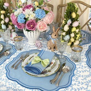 Easter-themed table setting with floral arrangements, bunny figurines, and decorative eggs.