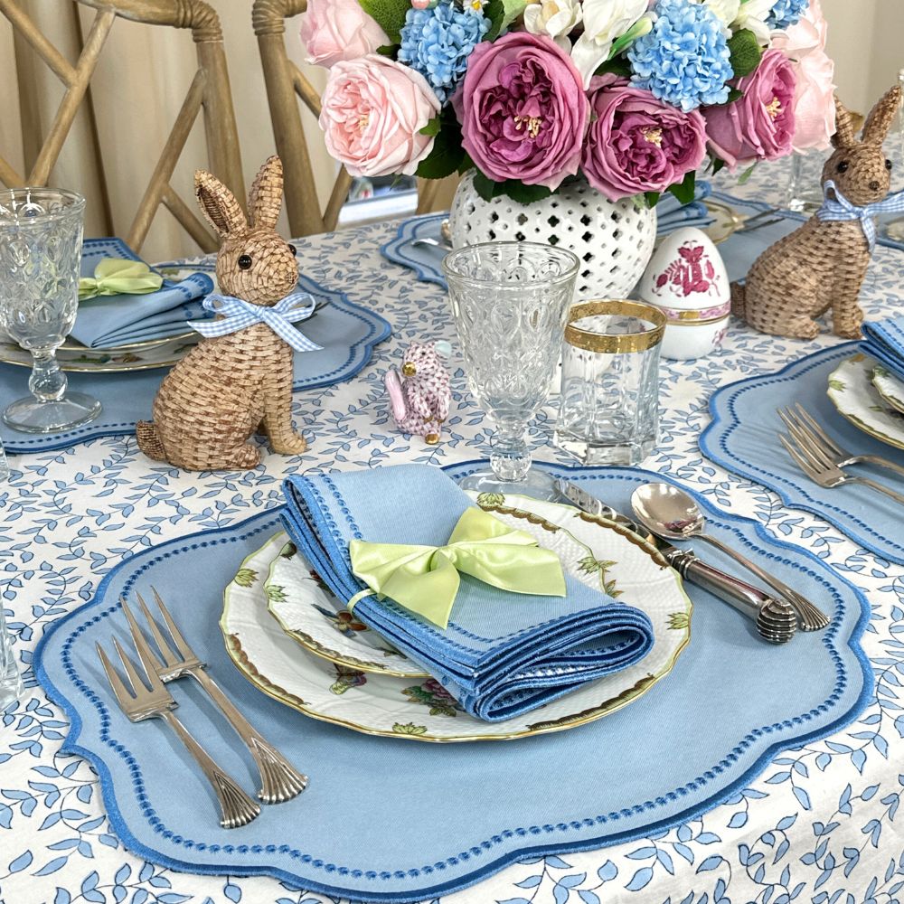 Easter table setting with bunny decorations, floral centerpiece, and blue place mats.
