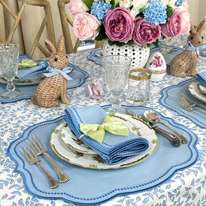 Easter table setting with bunny decorations, floral centerpiece, and blue place mats.