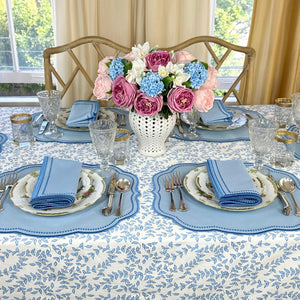 Elegant table setting with floral centerpiece, blue and white tablecloth, and silverware.