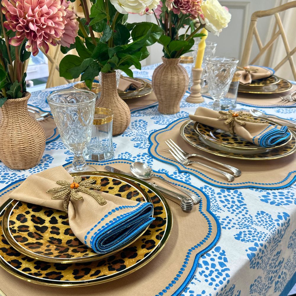 Elegant table setting with floral centerpieces, patterned tablecloth, and decorative plates. luxury embroidered placemat and napkins
