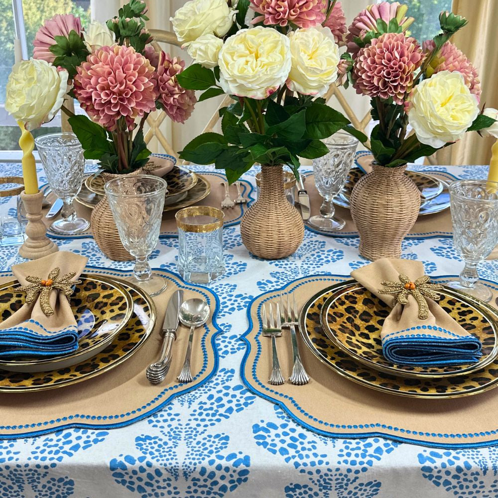 Elegant table setting with floral centerpieces, patterned tablecloth, and decorative plates. luxury embroidered placemat and napkins