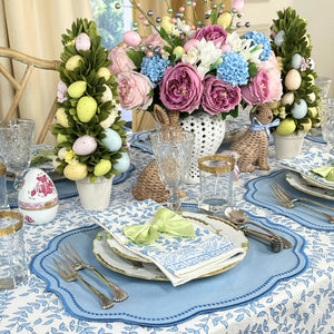 Easter-themed table setting with floral arrangements, eggs, and decorative items.