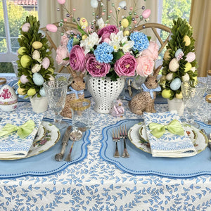 Easter-themed table setting with floral centerpiece, decorative eggs, and bunny figurines.