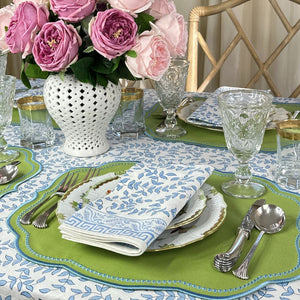 Elegant table setting with floral centerpiece, green placemats, and patterned plates. Blue leaves block print napkin . 