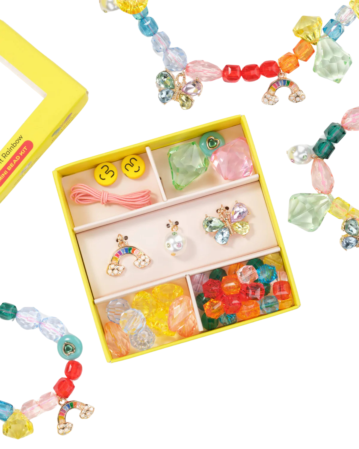 Top view of Make It Rainbow Mini Bead Kit showcasing colorful beads and three charms in a yellow box on black background