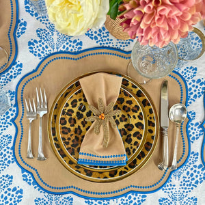 Decorative table setting with leopard print charger, gold rimmed plates, and colorful flowers.