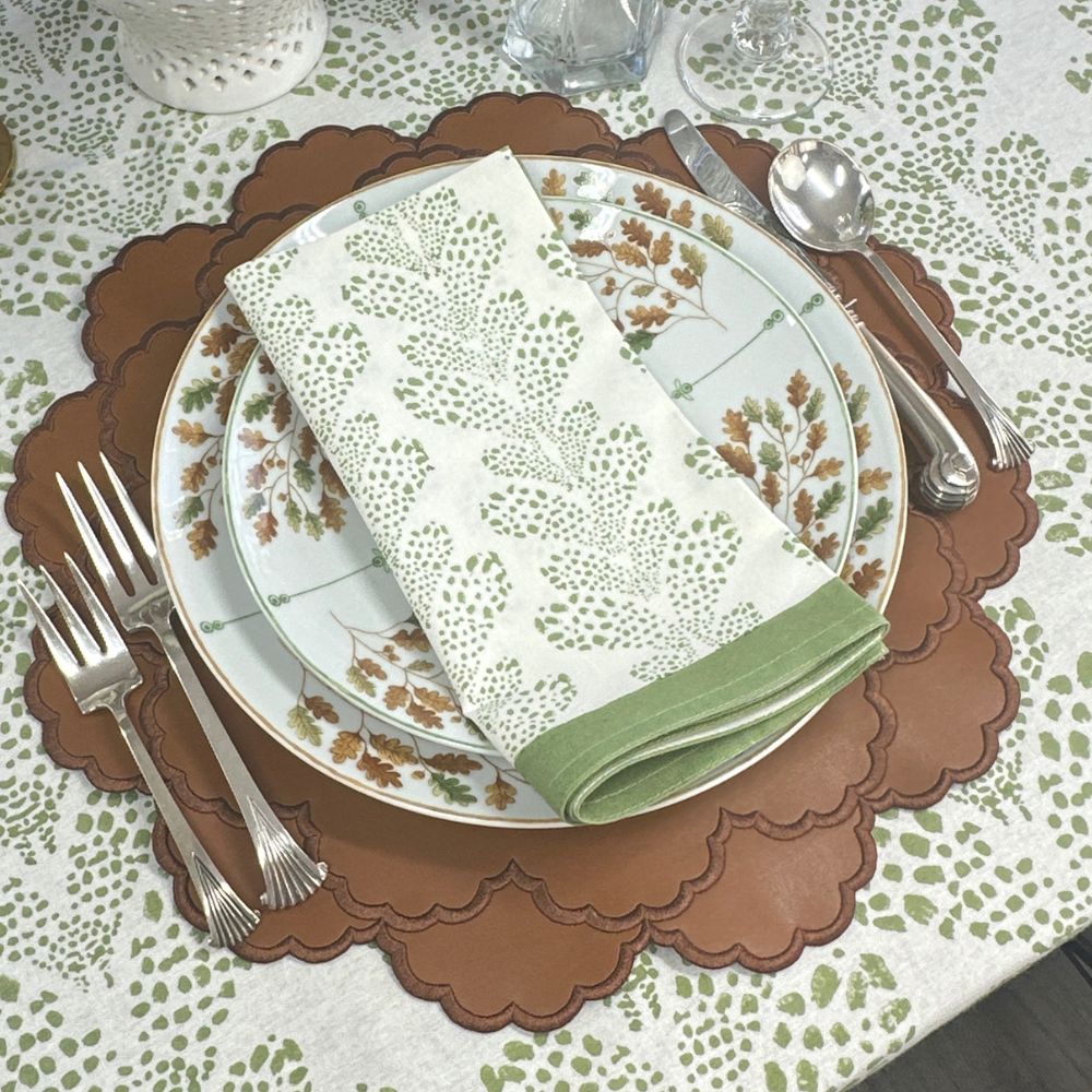 Dinner setting with a plate, napkin, and cutlery on a patterned tablecloth.