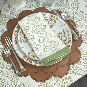 Dinner setting with a plate, napkin, and cutlery on a patterned tablecloth.