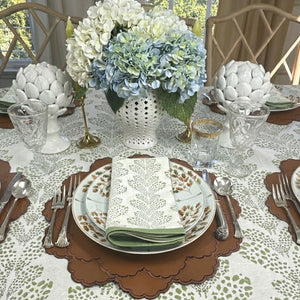 Elegant table setting with floral centerpiece, patterned plates, and cutlery on a white tablecloth.