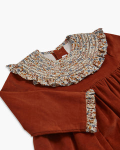 Brown dress with floral trim on a white background